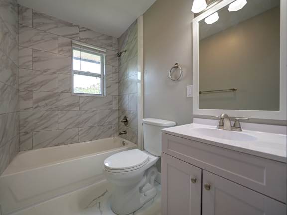 A white bathroom with a marble tiled shower.