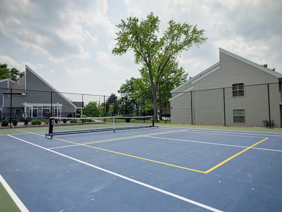 A tennis court with a yellow line in the middle and a building in the background.