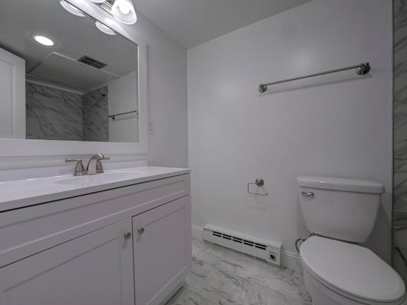 A white bathroom with a toilet, sink, and mirror.