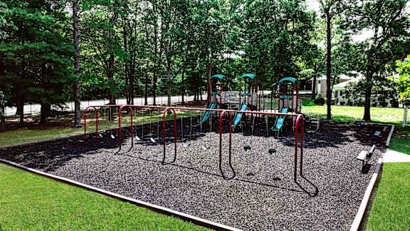 A playground with a red swing set and a green slide.
