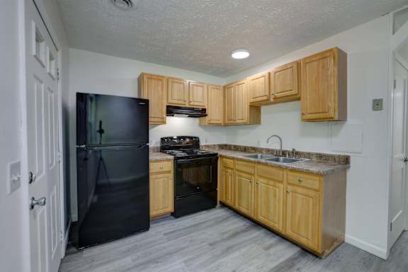 A kitchen with wooden cabinets and a black refrigerator.