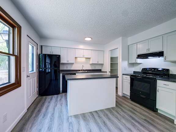 A kitchen with black appliances and white cabinets.