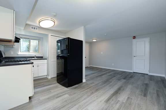 A kitchen with a black refrigerator and white cabinets.