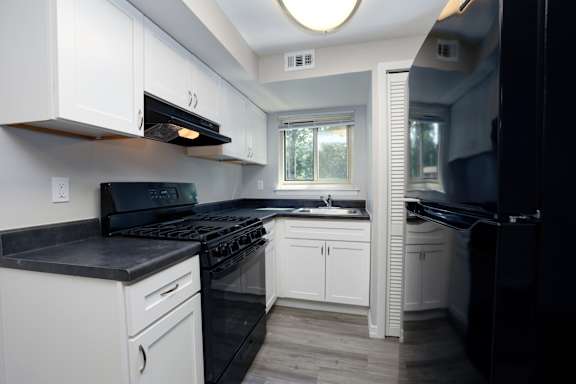 A kitchen with black appliances and white cabinets.