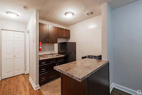 A kitchen with a granite countertop and wooden cabinets.