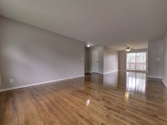 A room with wooden flooring and a door on the left side.
