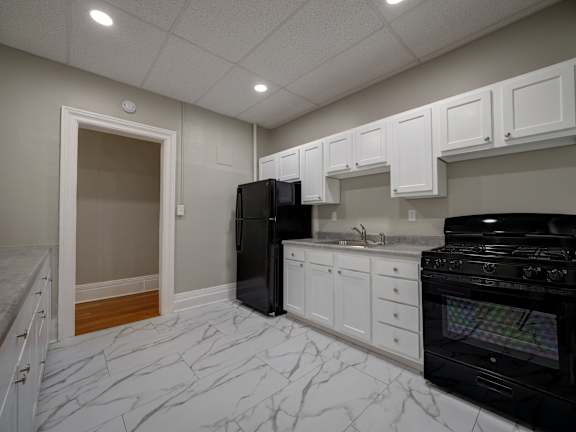 A kitchen with black appliances and white cabinets at Willett Apartments, Albany, New York