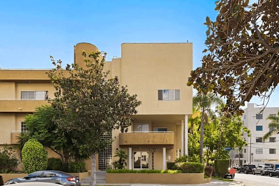 A beige building with a tree in front of it.