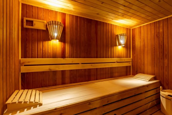 A wooden sauna with a bench and two lights on the wall.