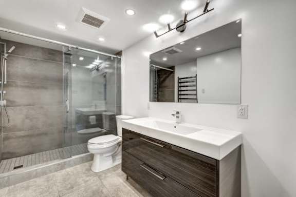 a bathroom with a toilet sink mirror and shower