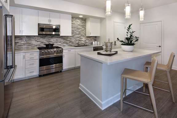 a kitchen with white cabinets and a large island with a white countertop