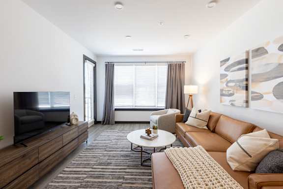 a living room with white walls and a large window