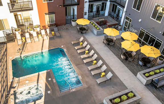 an overhead view of a swimming pool and patio with yellow umbrellas