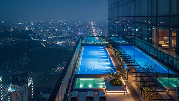 A long, illuminated swimming pool is lit up at night.