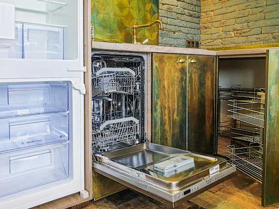 an open dishwasher in a kitchen with an open door