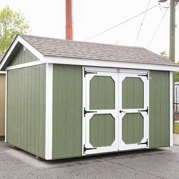 A green shed with white trim and a brown roof.