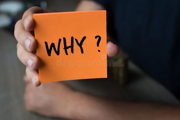 A person is holding a sticky note with the word "WHY?" written on it.