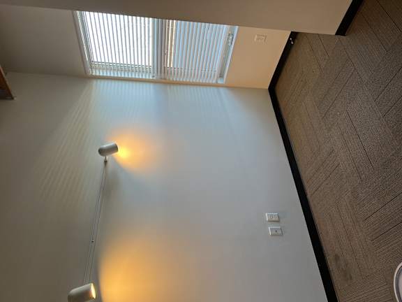 an empty room with a lamp on the wall and a window