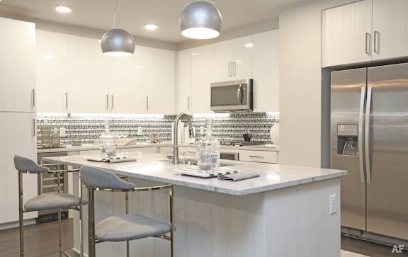 a kitchen with white cabinets and a large island with two stools
