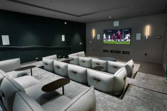 A room with a row of white couches and a television playing a sports game.