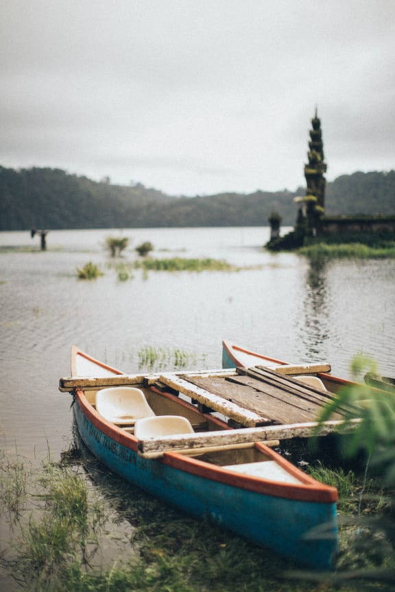 two boats sitting on the shore of a lake