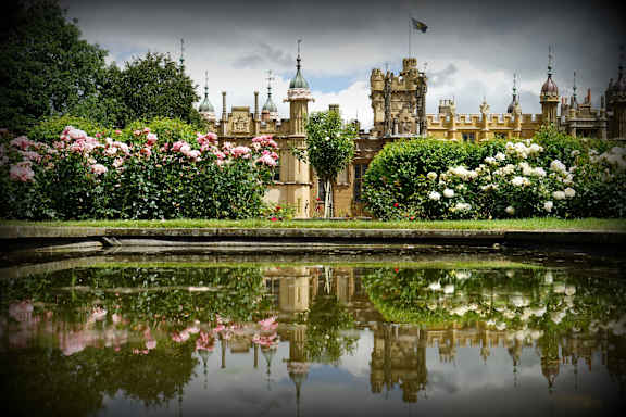a large castle with a pond in front of it