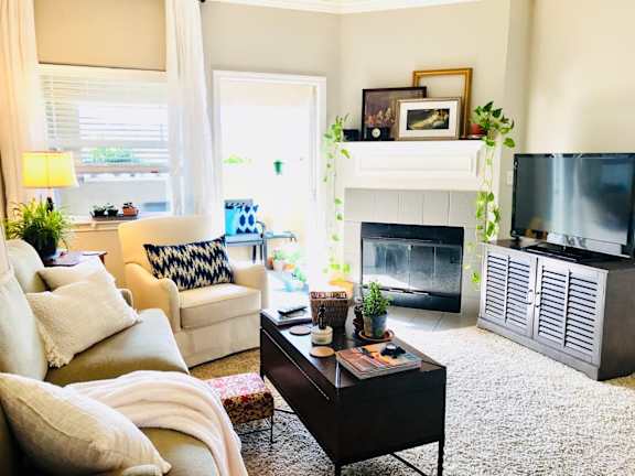 A living room with a fireplace, a couch, a chair, a coffee table, and a television.