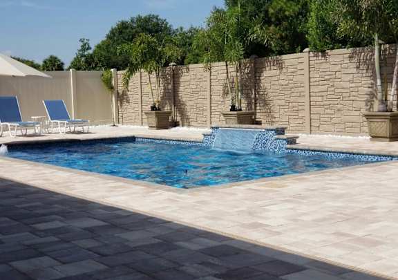 A pool with a waterfall and a stone wall.