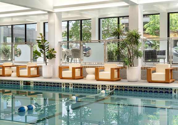 a swimming pool in a hotel with lounge chairs next to it