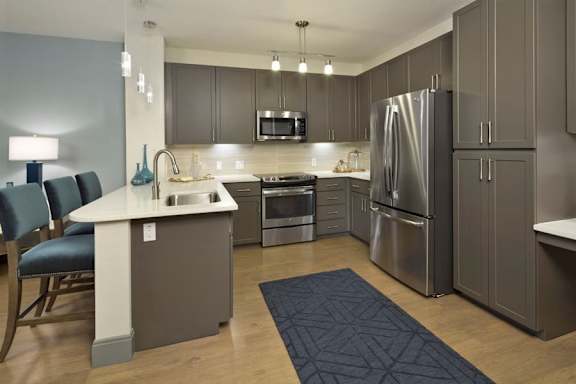 a kitchen with gray cabinets and stainless steel appliances