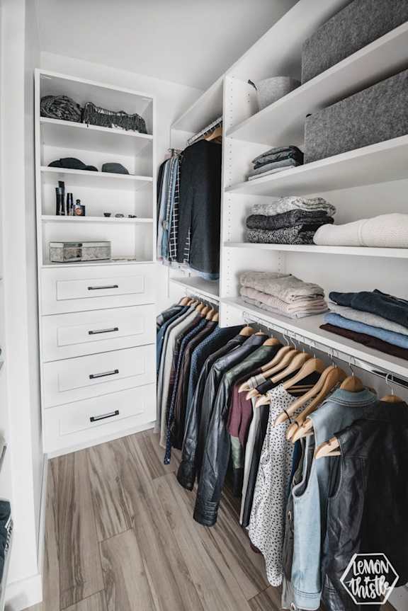 A well-organized closet with clothes and shelves.