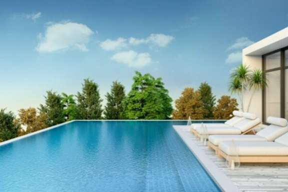 A swimming pool with lounge chairs and a house on the right side.
