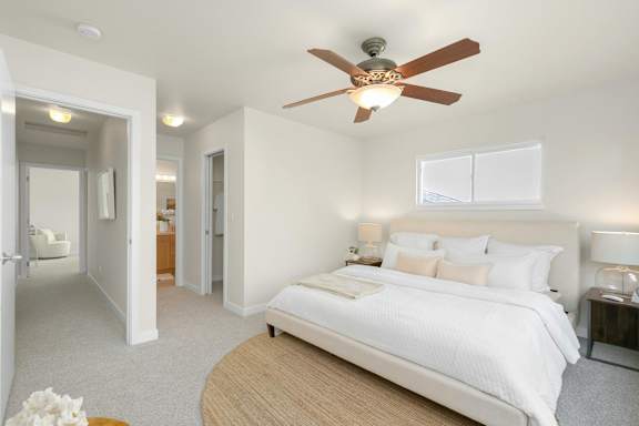 A bedroom with a large bed and a ceiling fan.