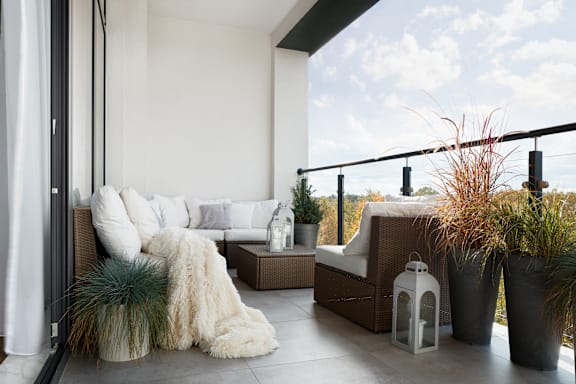 A white couch with a fur throw sits on a patio.