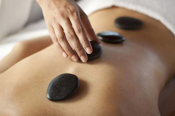 A person receiving a hot stone massage on their back.