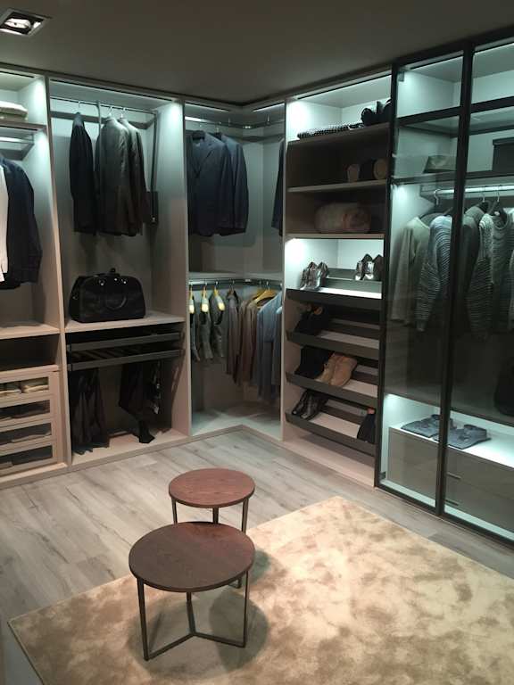 a walk in wardrobe with a small table and two stools