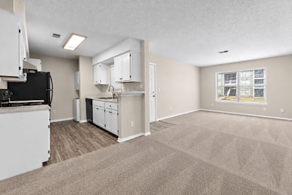 A kitchen with white cabinets and a black fridge is shown.