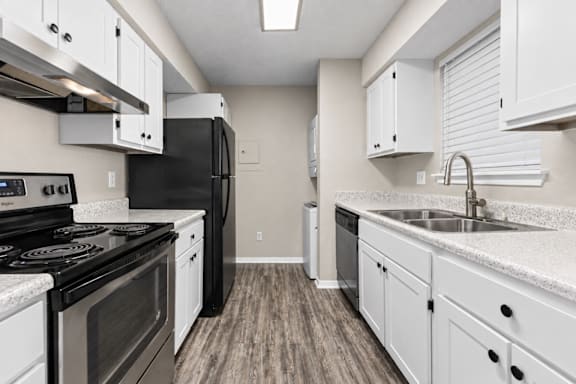 A kitchen with black appliances and white cabinets.