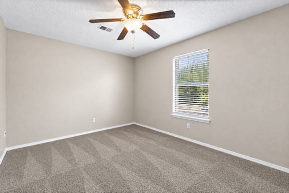 A room with a ceiling fan and a window with blinds.
