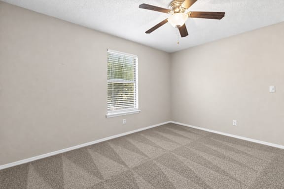 A room with a ceiling fan and a window with blinds.