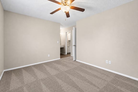A room with a ceiling fan and carpeted floor.