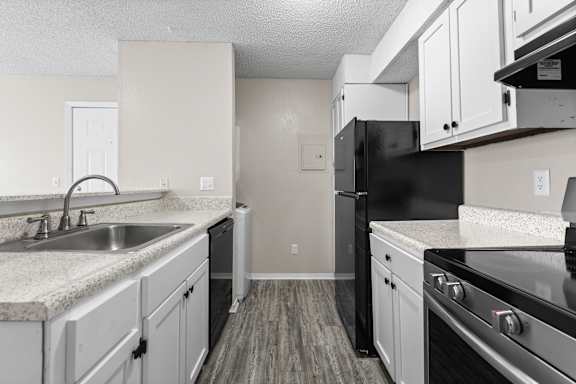 A kitchen with black appliances and white cabinets.