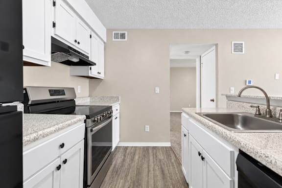 A kitchen with white cabinets and a black oven.