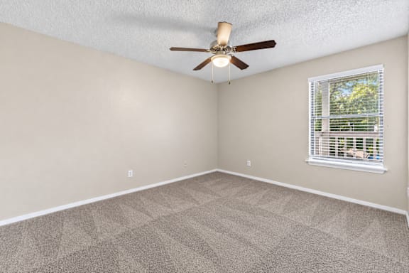 A room with a ceiling fan and a window with blinds.