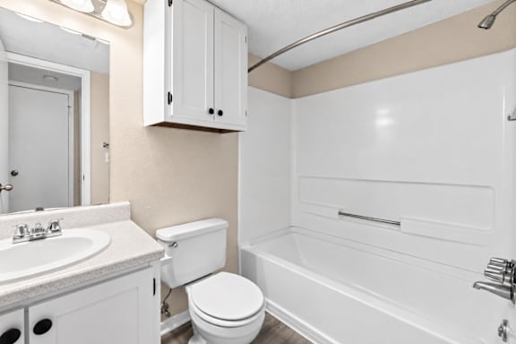 A white bathroom with a toilet, sink, and bathtub.