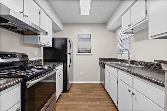 A kitchen with black appliances and white cabinets.