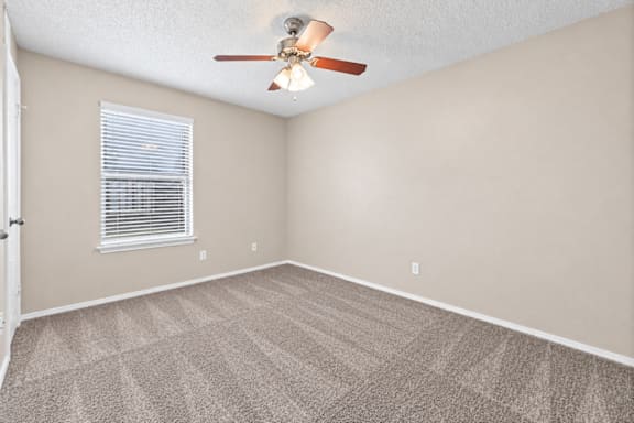 A room with a ceiling fan and carpeted floor.