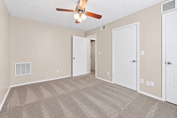 A room with a ceiling fan and carpeted floor.