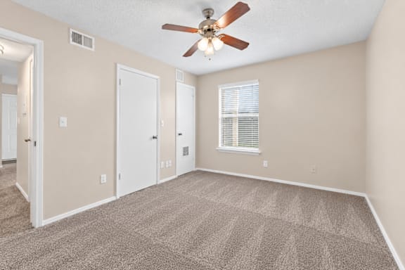 A room with a ceiling fan and carpeted floor.