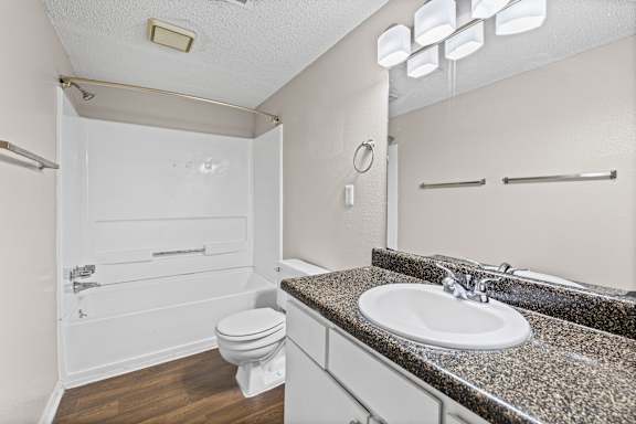 A bathroom with a granite countertop and a white toilet.